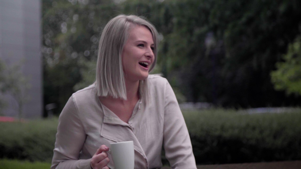 Enterprise Mobility team member in conversation while drinking from a mug.