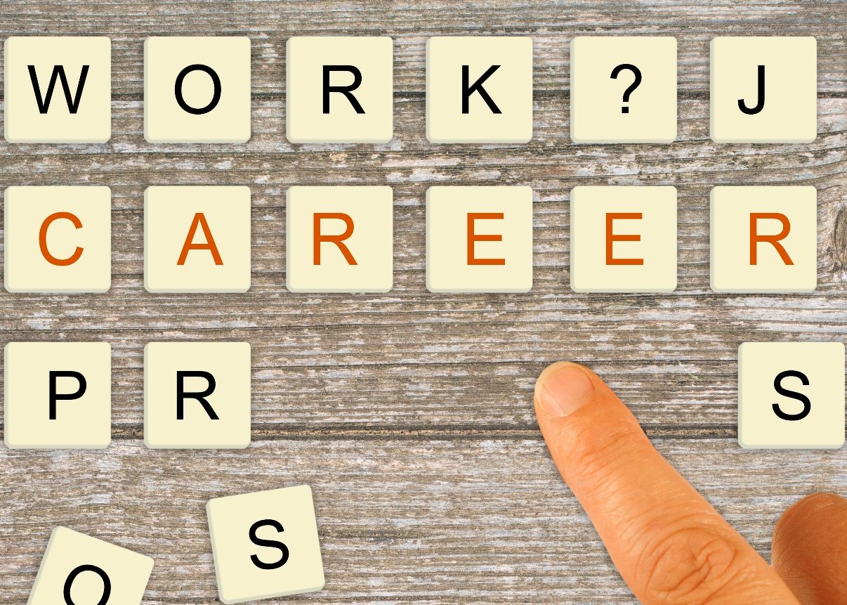 Letter tiles being arranged by a finger to spell "work", "job", "career" and then extra tiles scattered about