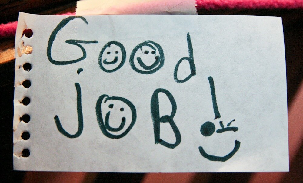 Piece of notebook paper that says "good job" with smiley faces