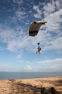 People about to land on the beach after skydiving