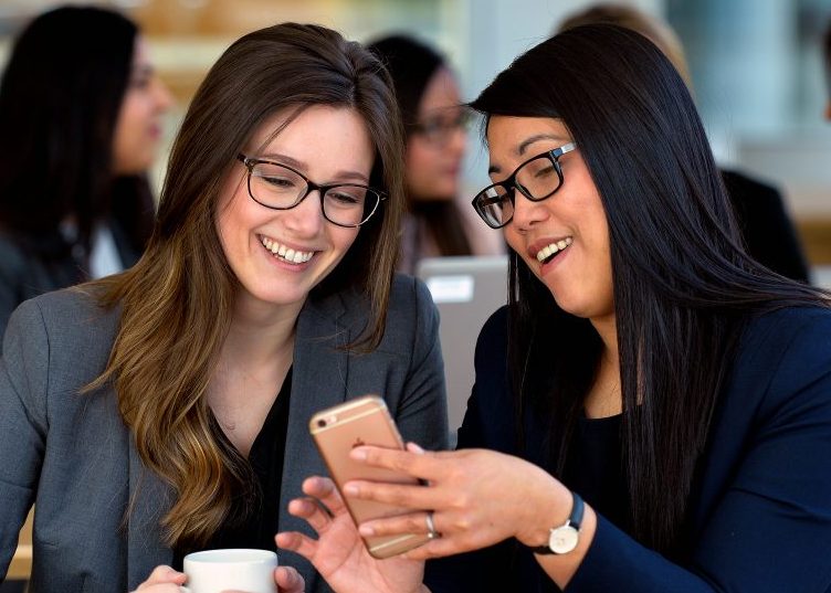 Two women smiling and looking at a cellphone