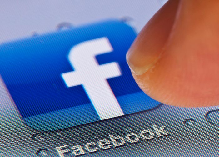Finger pressing Facebook app icon