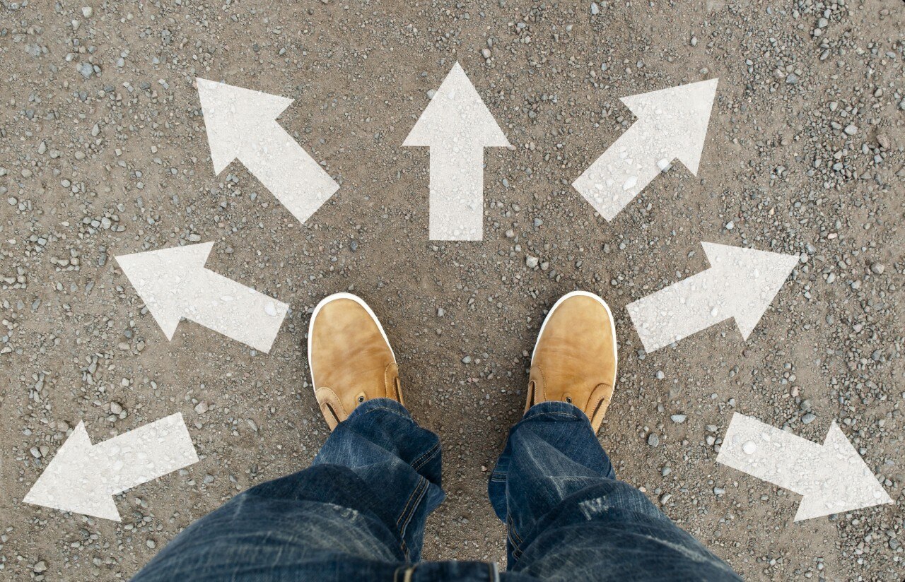 Feet on pavement surrounded by arrows pointing different directions