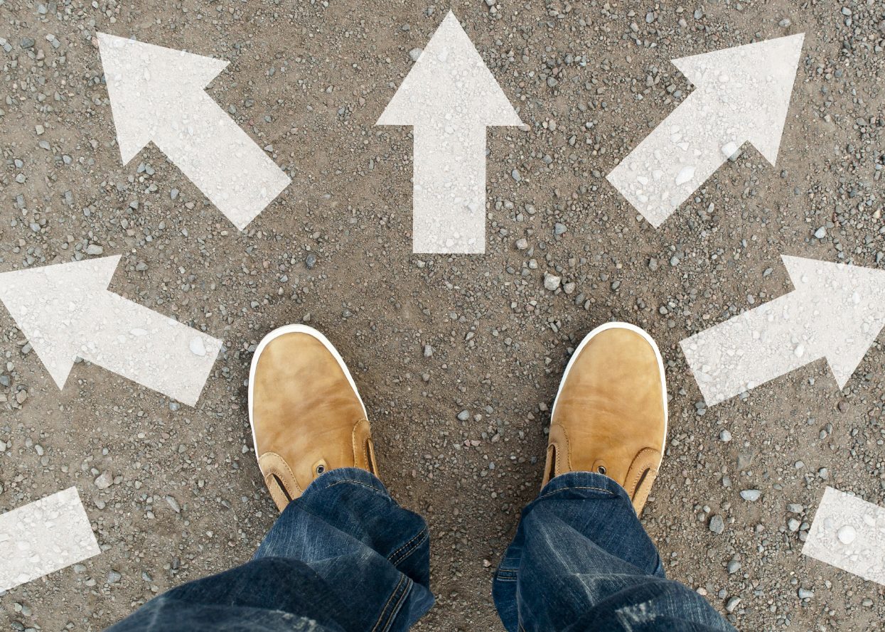 Feet on pavement surrounded by arrows pointing different directions