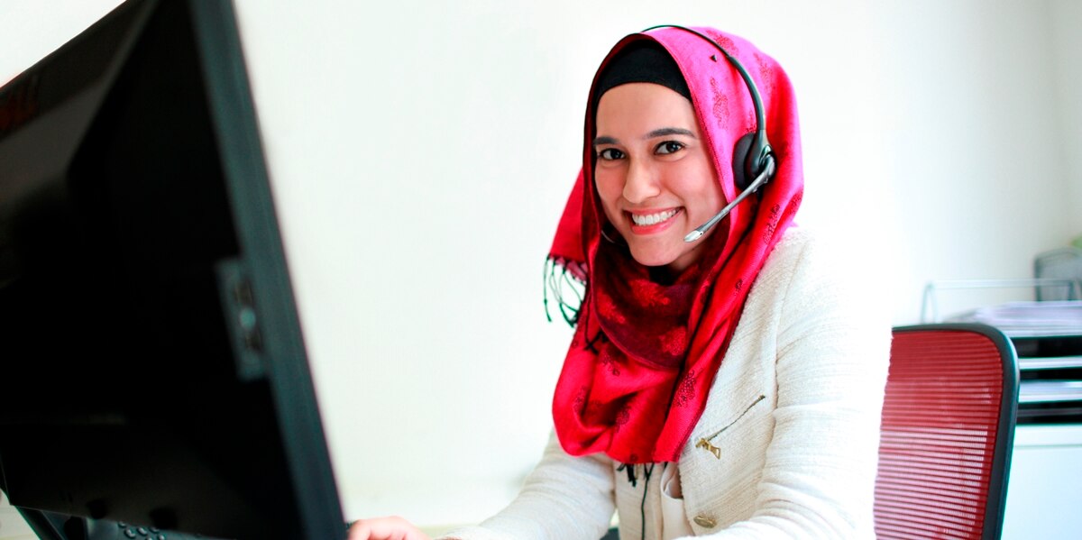 Smiling lady working from home with a headset on sitting at a computer