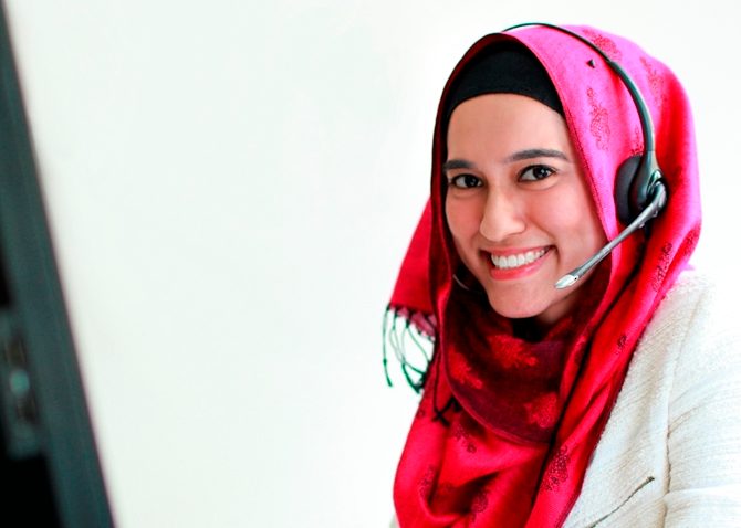 Smiling lady working from home with a headset on sitting at a computer