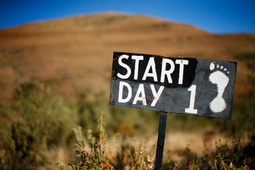 Sign in the wilderness that is painted with a human footprint and says "Start day 1"