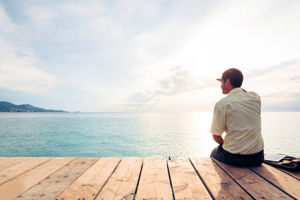 Man sitting on deck overlooking ocean
