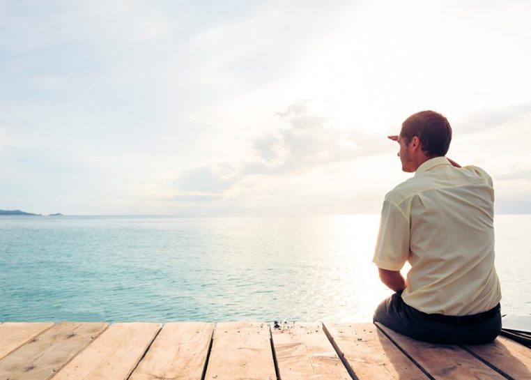 Man sitting on deck overlooking ocean