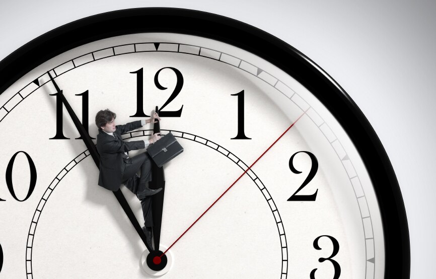 A man with a briefcase riding the hour hand of a clock