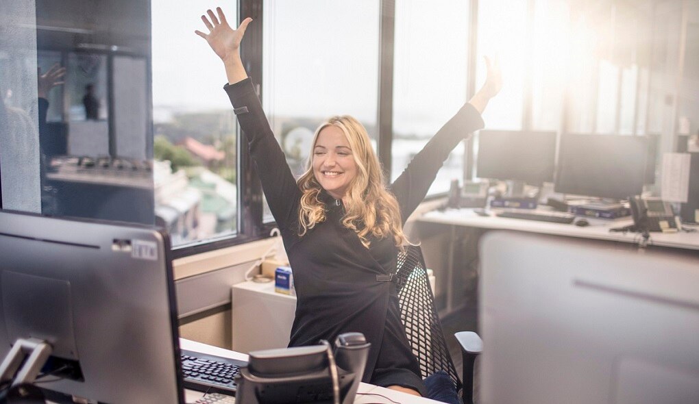 Ella throwing her hands up in excitement at her desk