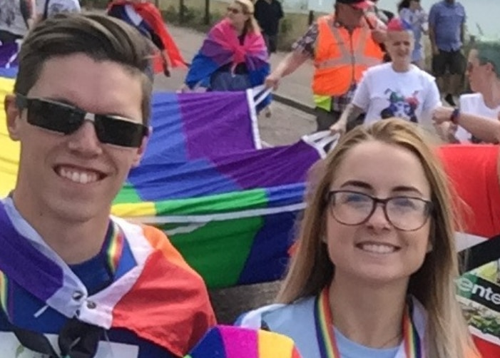 Luke and other Enterprise Employees with the large PRIDE flag at a parade