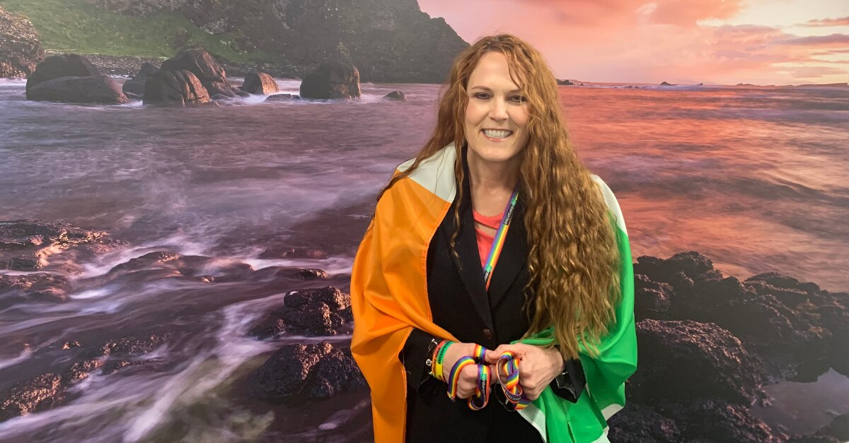 Leslee with Irish Flag around her shoulders in front of ocean