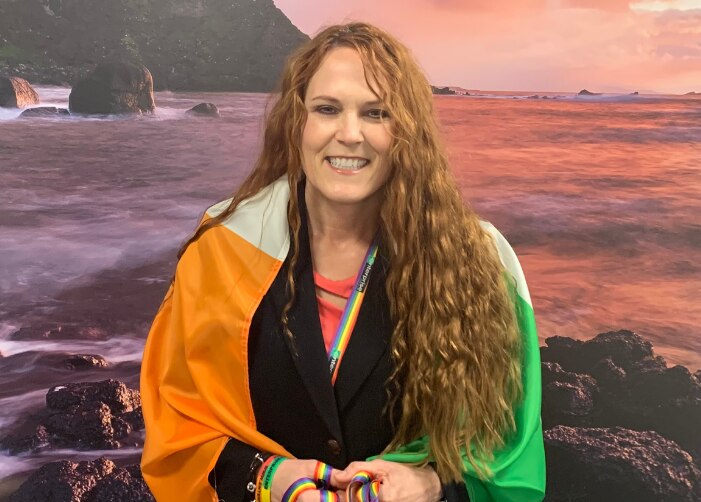 Leslee with Irish Flag around her shoulders in front of ocean