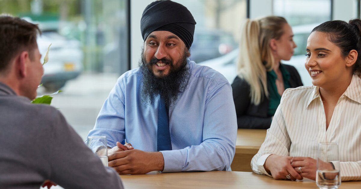 Three Enterprise Mobility team members sitting down at a table networking