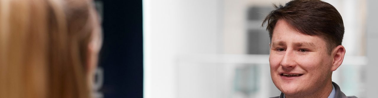 Enterprise Mobility team member sitting across another team member, who has a laptop open in front of her. 