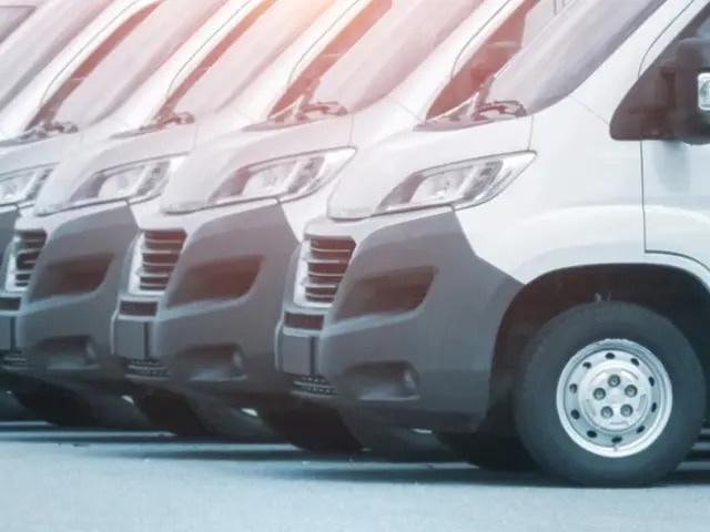 A long row of white passenger vans.